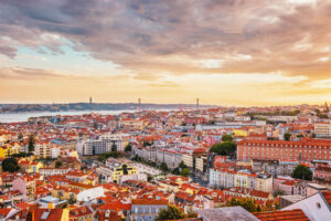 View of Lisbon famous view from Miradouro da Senhora do Monte tourist viewpoint of Alfama and Mauraria old city district, 25th of April Bridge at sunset. Lisbon, Portugal