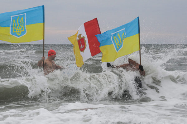 Άνδρες με ουκρανικές σημαίες βουτούν στα παγωμένα νερά για τον εορτασμό των Θεοφανείων στην Οδησσό κι ενώ η Ουκρανία βρίσκεται σε πόλεμο μετά την ρωσική εισβολή στα εδάφη της