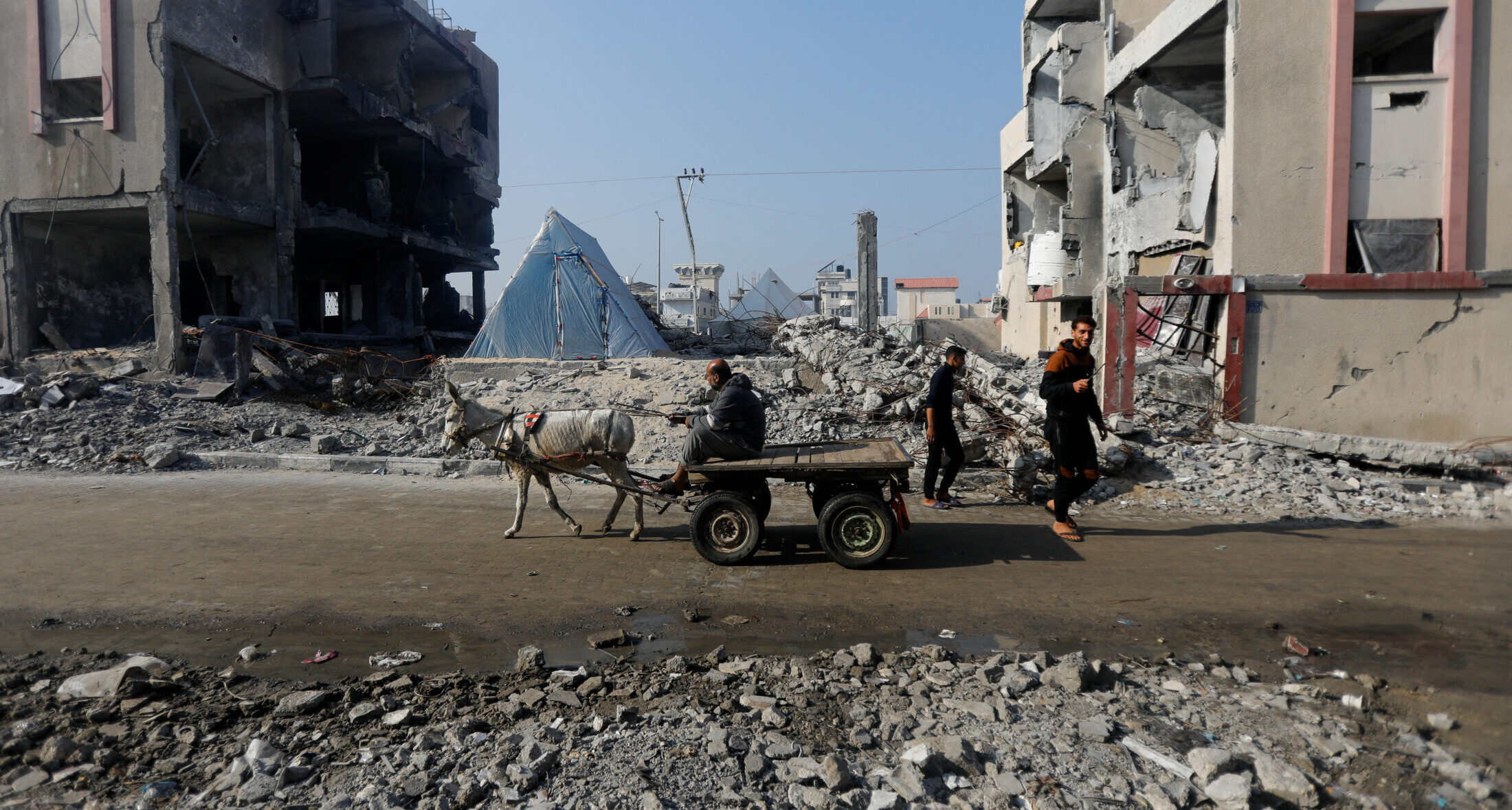 Ένα γαϊδούρι που τραβάει ένα κάρο, περνάει μπροστά από τα ερείπια ενός σπιτιού που καταστράφηκε από ισραηλινό χτύπημα στη Γάζα