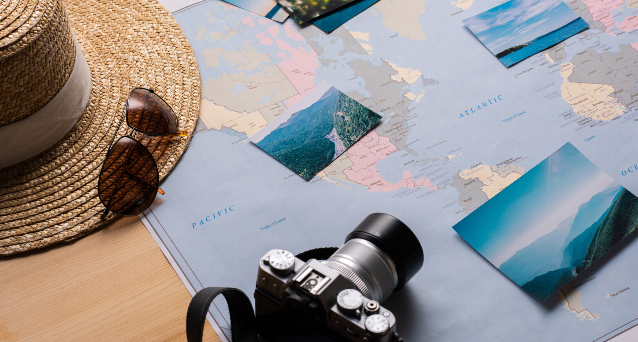 Κοντινό πλάνο σε παγκόσμιο χάρτη, με φωτογραφίες από φύση, φωτογραφική μηχανή, γυαλιά ηλίου και καπέλο