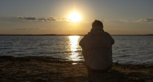 Άνδρας απολαμβάνει τη μοναξιά του δίπλα στη θάλασσα την ώρα ου ηλιοβασιλέματος