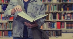 Σπουδαστής κρατά ένα βιβλίο σε μια βιβλιοθήκη