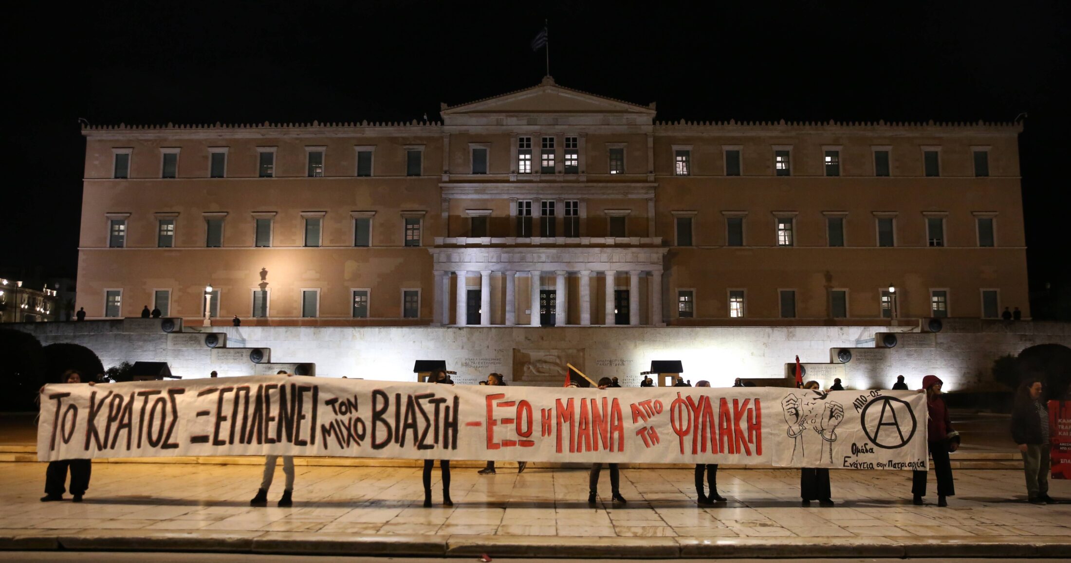 Διαδηλωτές κρατούν πανό κατά τη διάρκεια της συγγκέντρωσης διαμαρτυρίας για την πρόταση του Εισαγγελέα, στη δίκη, η οποία αθωώνει τον κστηγορούμενο Ηλία Μίχο για τον βιασμό και την έκδοση της 12χρονης στον Κολωνό