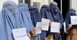 Αφγανές γυναίκες κρατούν χαρτιά που γράφουν στα νταρί «Το μήνυμα του Χατζ είναι όχι στις διακρίσεις», για να διεκδικήσουν τα δικαιώματά τους στην εκπαίδευση και την απασχόληση