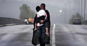 Πρόσφυγας κρατάει σφιχτά το παιδί του στη βροχή στα σύνορα Ελλάδας - Βόρειας Μακεδονίας. Η φωτογραφία αυτή βραβεύτηκε με Πούλιτζερ