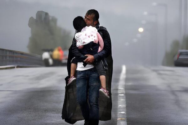 Πρόσφυγας κρατάει σφιχτά το παιδί του στη βροχή στα σύνορα Ελλάδας - Βόρειας Μακεδονίας. Η φωτογραφία αυτή βραβεύτηκε με Πούλιτζερ