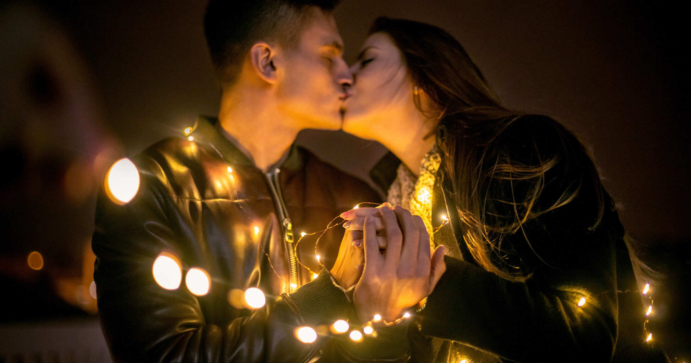 young-couple-kissing-hugging-outdoor-night-street-christmas-time (1)